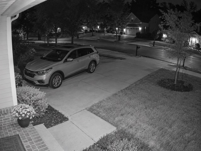 Conceptual infrared surveillance view of a home driveway and front yard at night